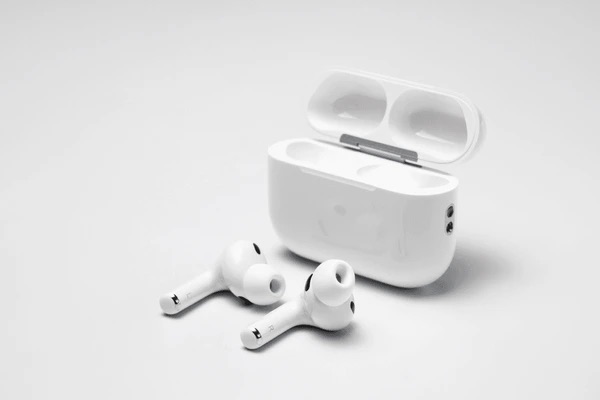 Custodia aperta con due AirPods Pro 3 bianchi appoggiati davanti su sfondo chiaro.